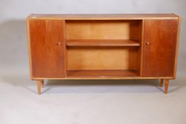 A mid century teak dwarf bookcase with two doors flanking open shelves, 54" x 10" x 30"