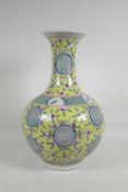 A Chinese polychrome porcelain vase decorated with auspicious symbols, bats & peaches, on a yellow