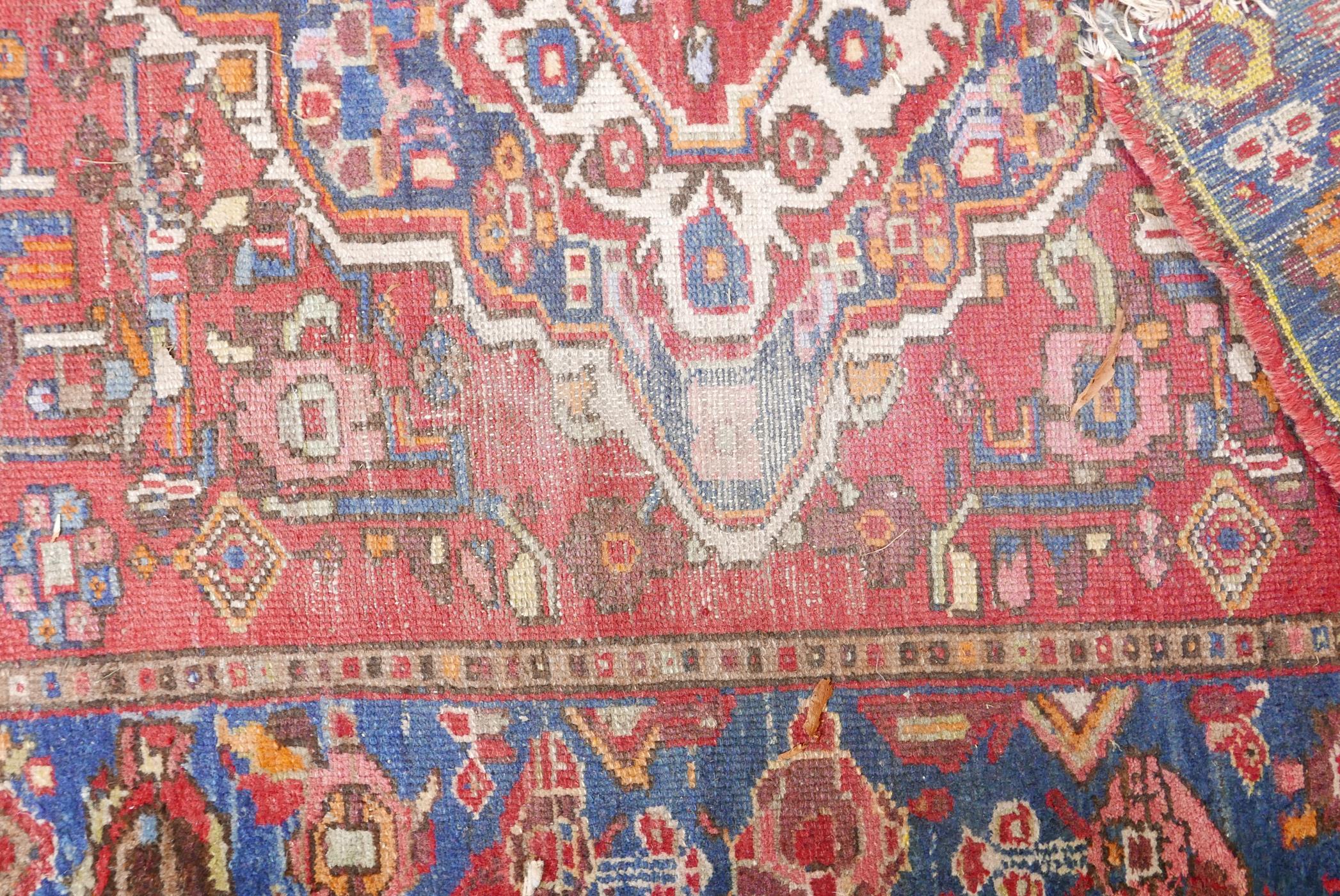 A Persian red ground wool carpet with a central floral medallion design and blue borders, 83" x 52" - Image 4 of 4