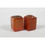 A pair of Chinese amber soapstone seals, decorated with carp, lotus flowers & a dragon head, 1½"