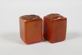 A pair of Chinese amber soapstone seals, decorated with carp, lotus flowers & a dragon head, 1½"