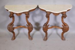 A pair of serpentine shaped carved wood console tables with marble tops, raised on winged griffin