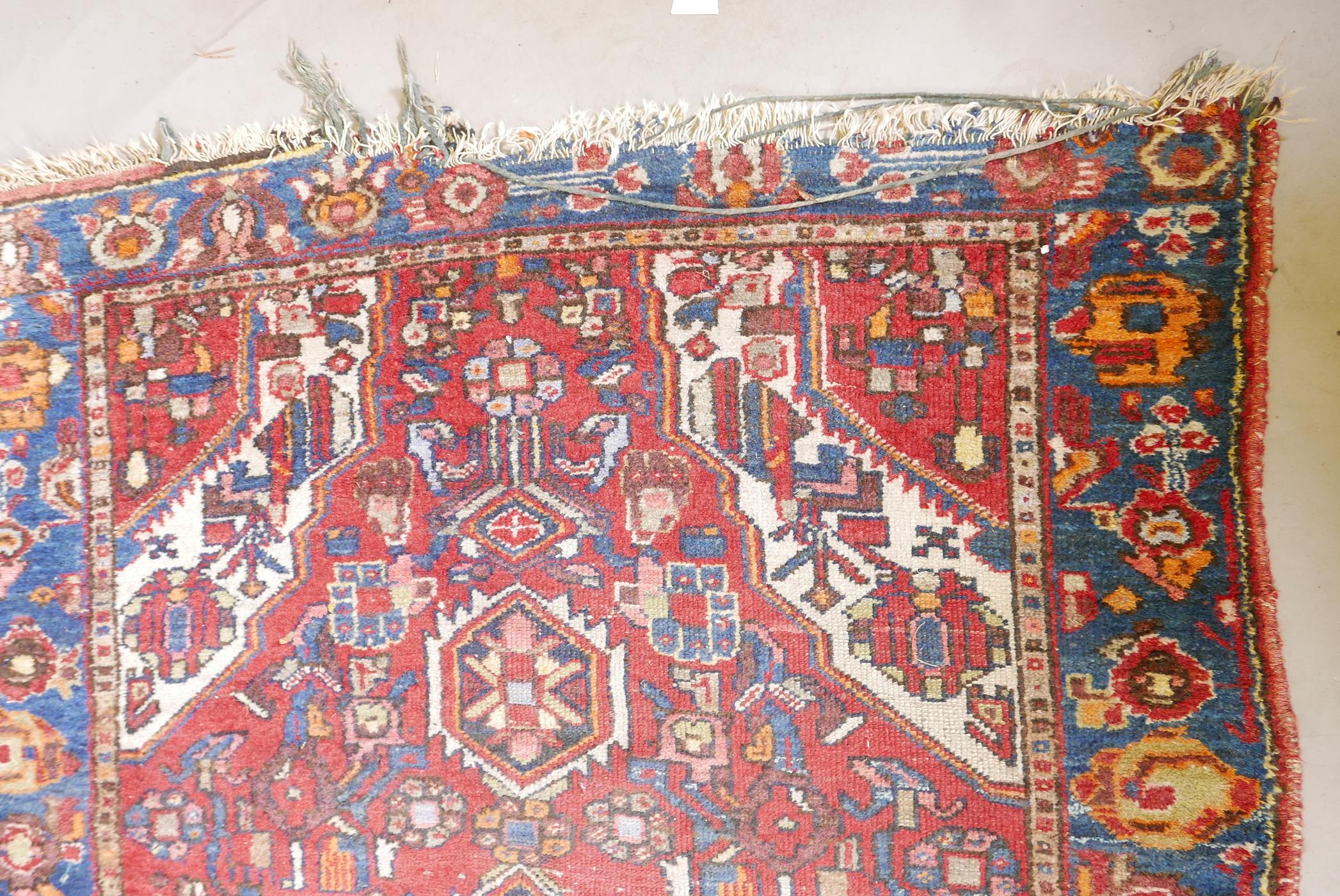A Persian red ground wool carpet with a central floral medallion design and blue borders, 83" x 52" - Image 2 of 4