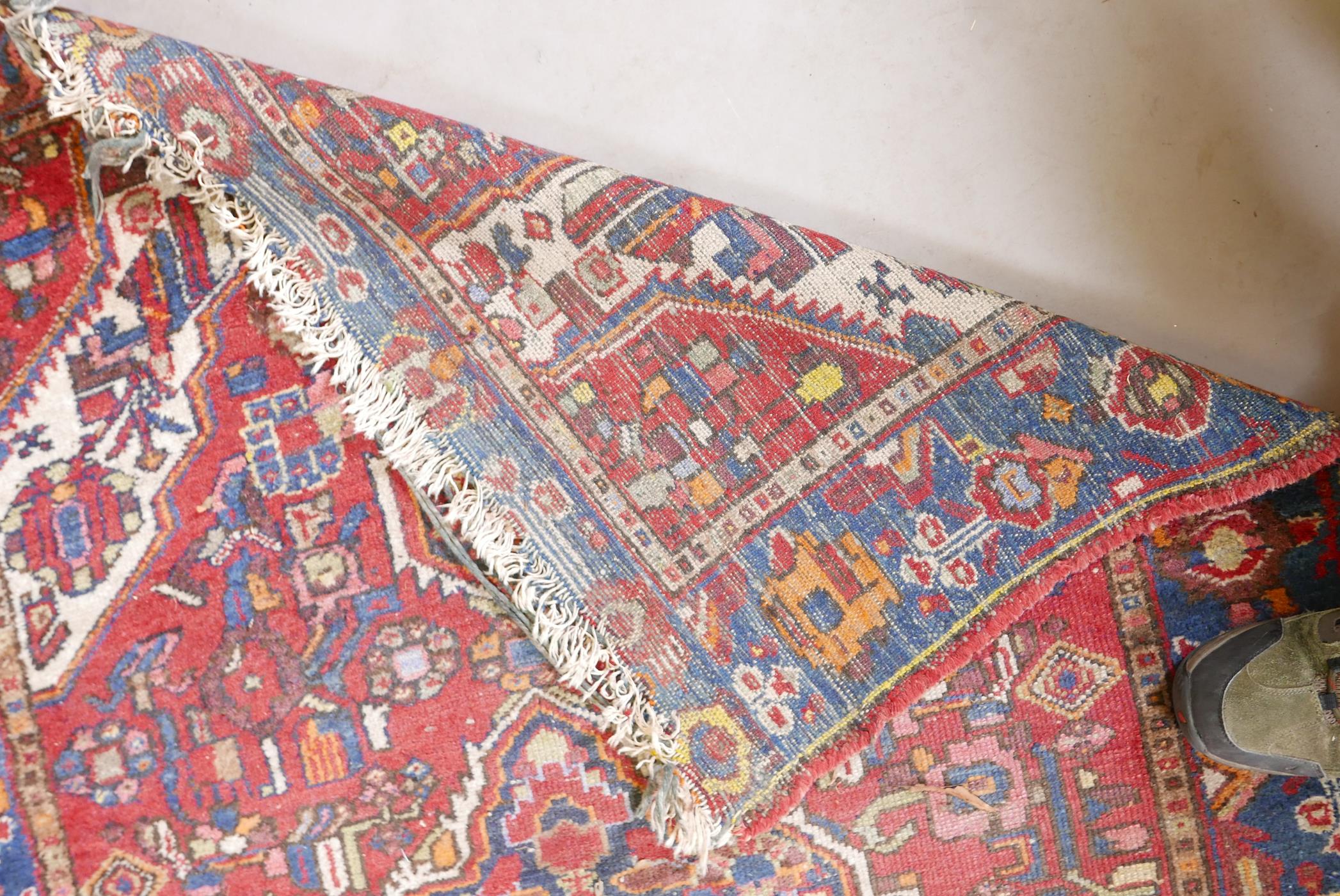 A Persian red ground wool carpet with a central floral medallion design and blue borders, 83" x 52" - Image 3 of 4