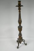 A turned bronze candlestick on a tripod base, 28" high