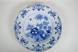 An C18th/C19th Delft blue and white charger with hand painted decoration of a garden landscape,