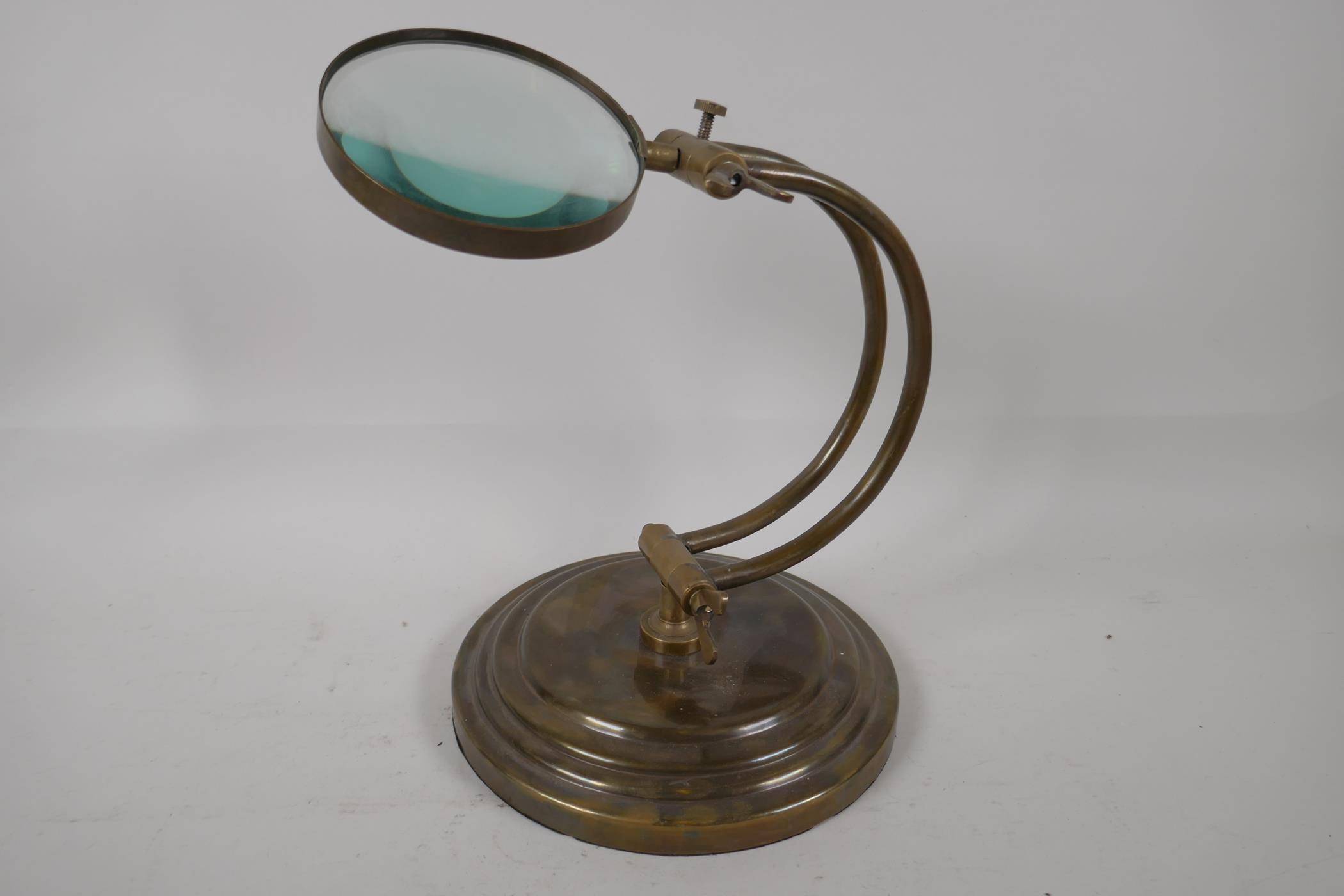 A brass desk top magnifying glass on adjustable stand, 10" high