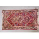 A Persian wool rug with a central triple medallion design on a tomato red field, 31" x 57"