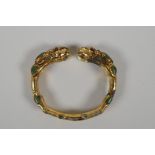 A gilt metal bangle with twin dragon head decoration, set with turquoise stones. 3" x 2½"