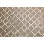 A black ground woven wool carpet, with a natural coloured repeating geometric pattern. 74" x 110"