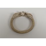 A Chinese white metal wirework bangle decorated with two dragon heads. 3½" x 3"
