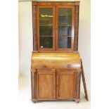 A Victorian cylinder top bureau bookcase, the upper section with two glazed doors and carved