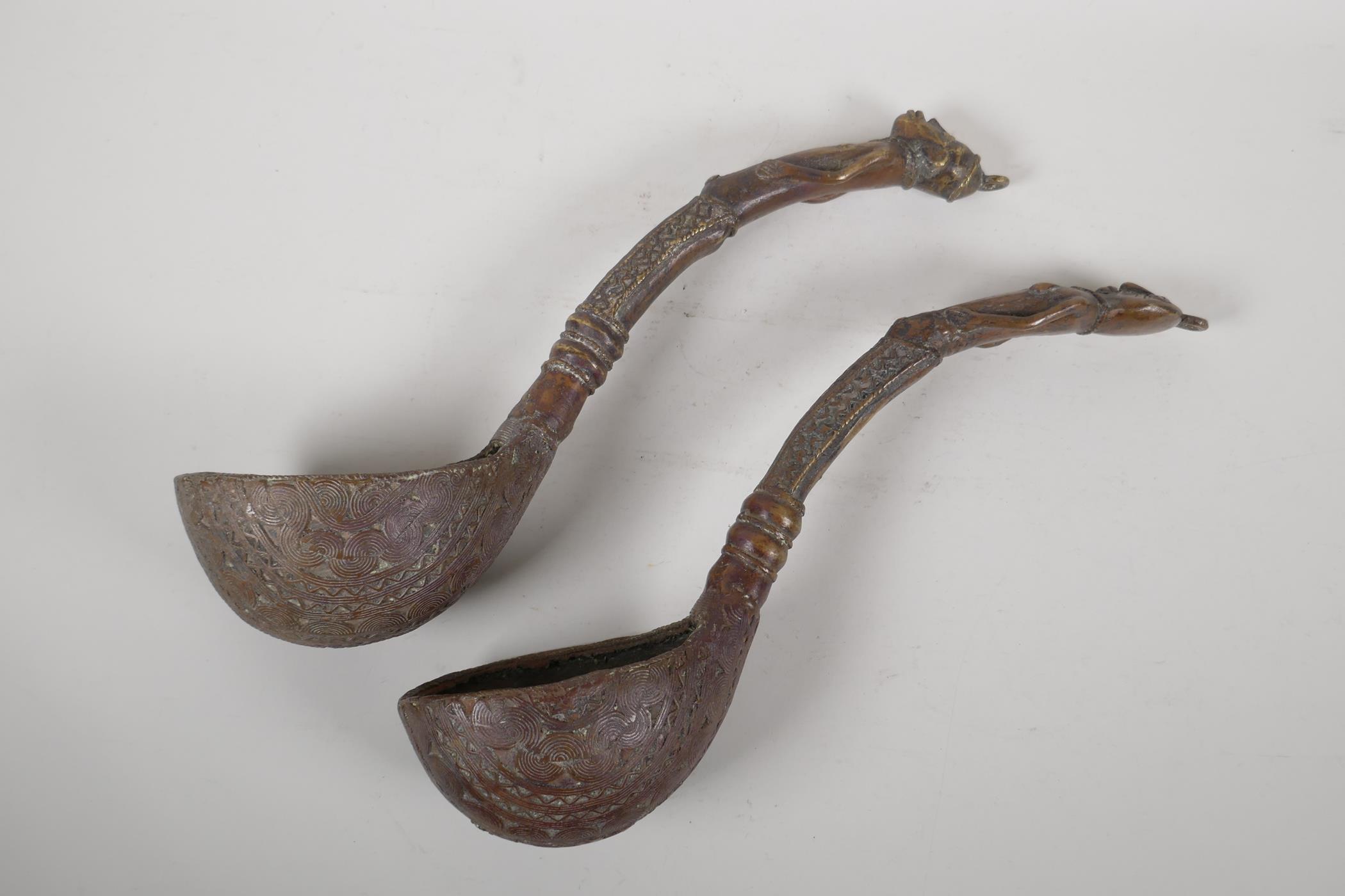 A pair of African brass ladles with figural handles. 15" long