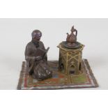 A gold painted bronze inkwell, modelled as an Arab gentleman reading, beside a table that forms