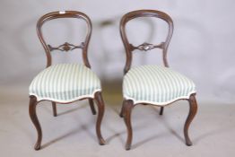 A pair of Victorian walnut balloon back side chairs, with carved and pierced back rails, raised on