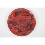 A Chinese cinnabar lacquer style dish, with carved decoration of temples in a riverside landscape,