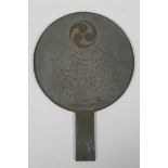 A Japanese bronze hand mirror, decorated with the Mitsudomoe, a fruit bearing bush, and character