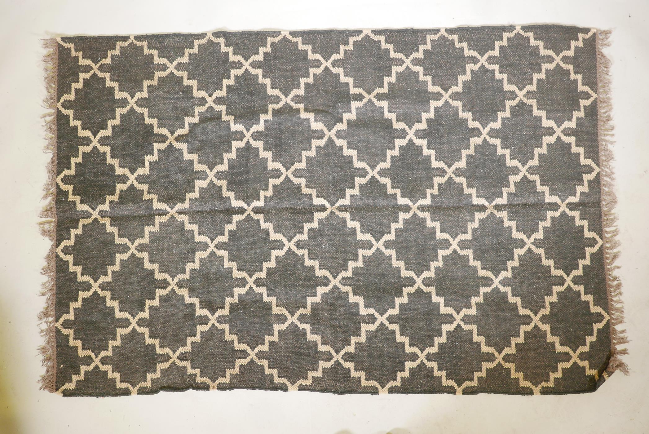 A pair of black ground, woven wool rugs, with a natural coloured repeating geometric pattern. 73" - Image 2 of 4