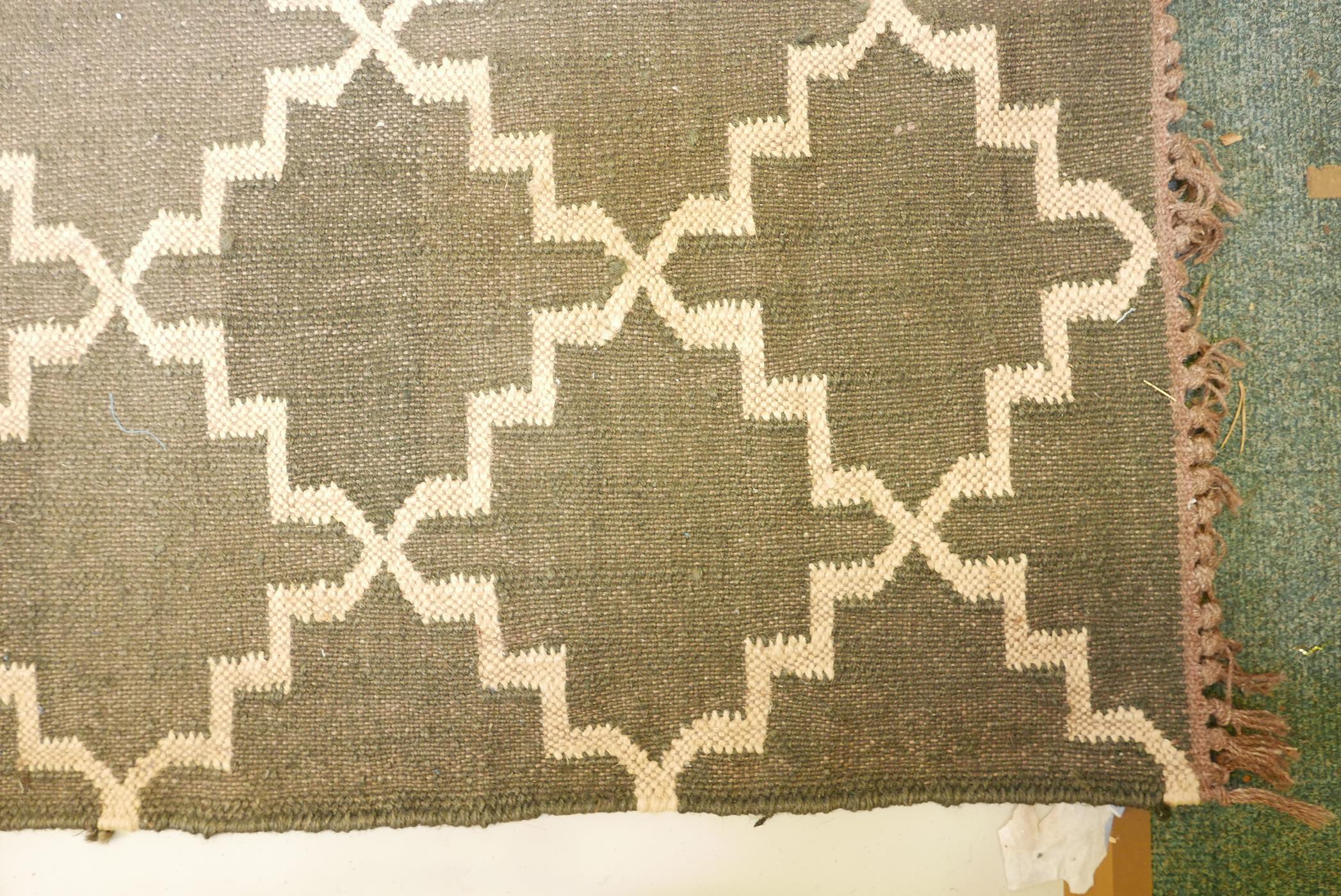 A black ground woven wool carpet, with a natural coloured repeating geometric pattern. 74" x 110" - Image 3 of 4