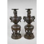A pair of Japenese Meiji bronze stands, with elephant mark handles & decorative panels depicting