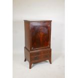 An early C20th figured mahogany music/folio cabinet. Fitted with shelves over two drawers and