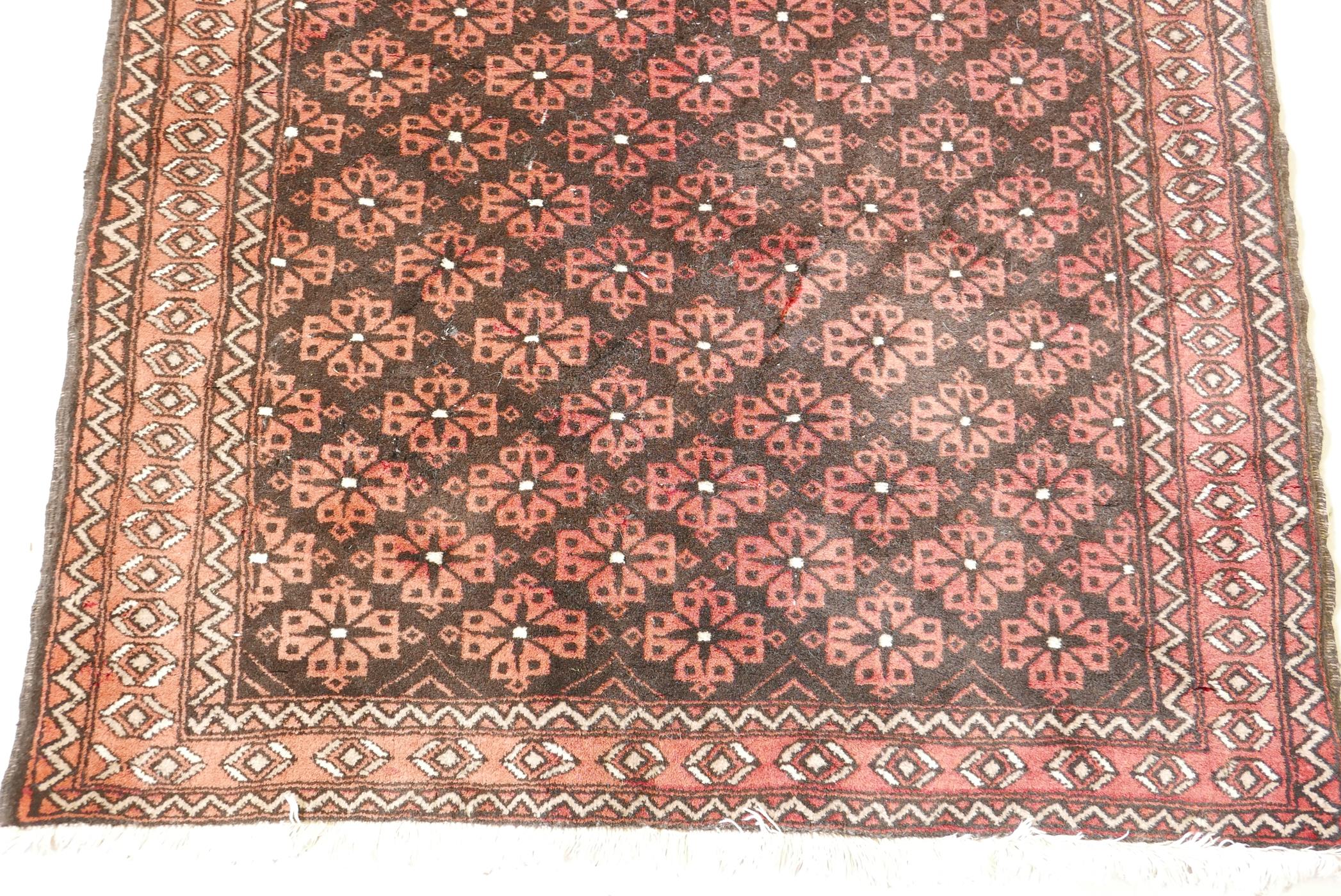 A hand woven rug with geometric floral design, on a faded red field. 41" x 78" - Image 2 of 3