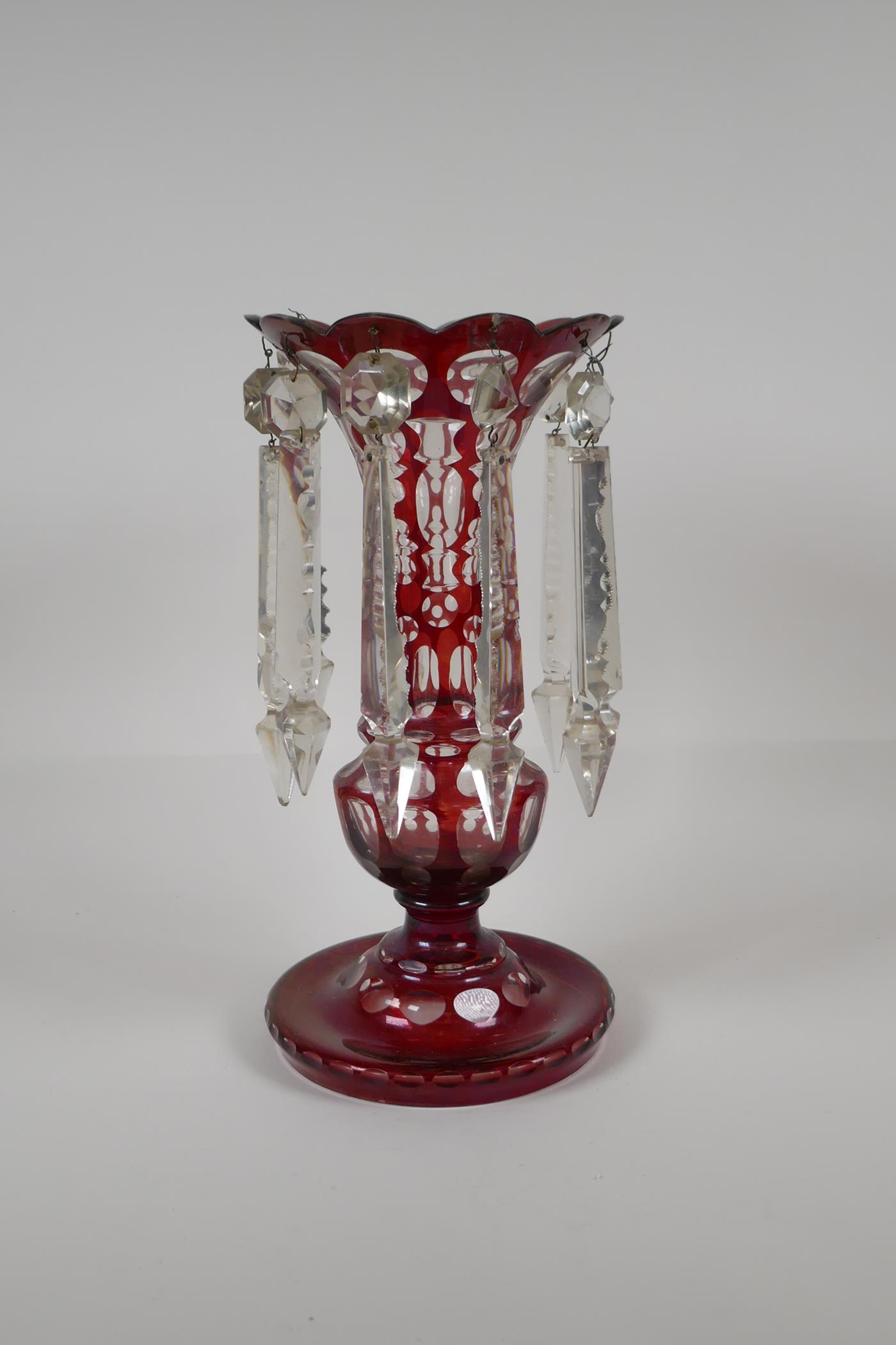 A Bohemian ruby glass lustre with slice cut decoration, 1 lustre missing, 12½" high
