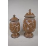 Two French stoneware lidded storage jars on pedestal bases, having painted scrool decoration.