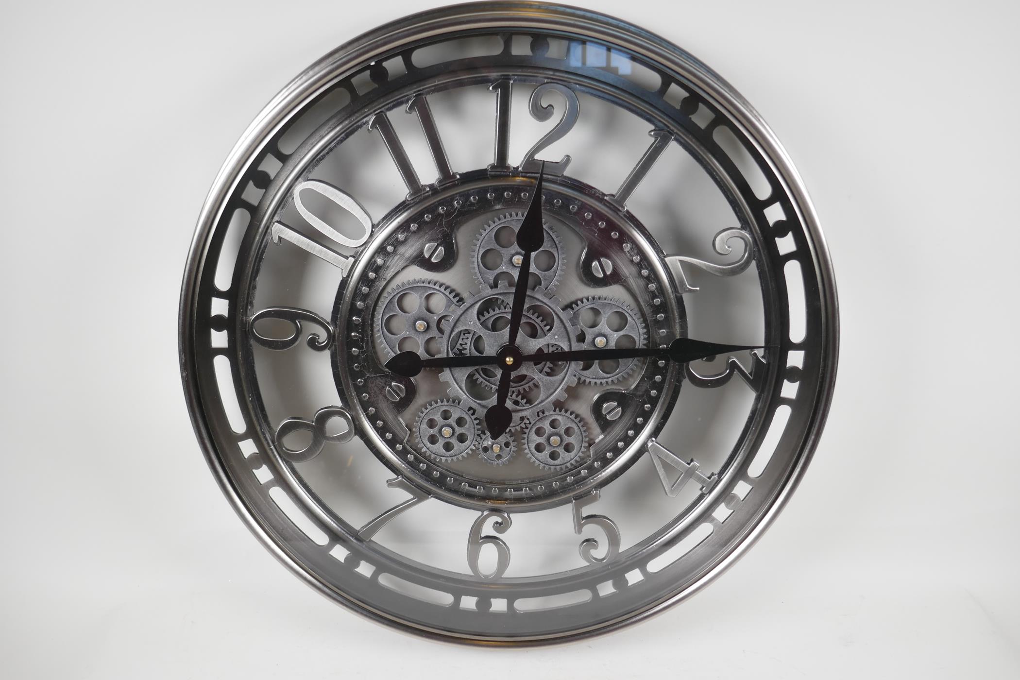 A large wall clock with open gear wheel decoration and Arabic numerals. 21" diameter