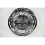 A large wall clock with open gear wheel decoration and Arabic numerals. 21" diameter