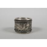 A Chinese white metal archers thumb ring with a revolving cuff decorated with a dragon and