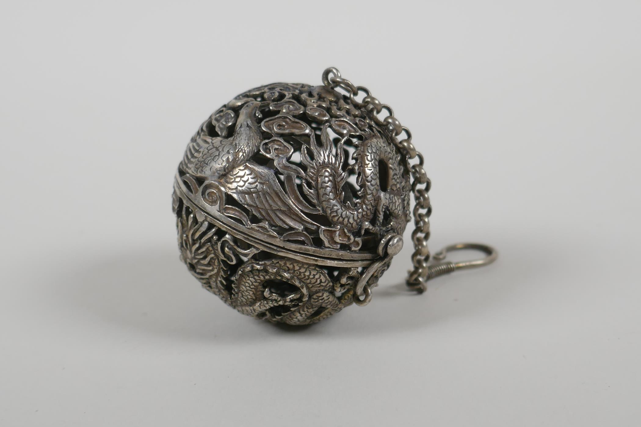 A Chinese white metal pierced ball incense burner, with a gimbal mouted reservoir, 2" diameter