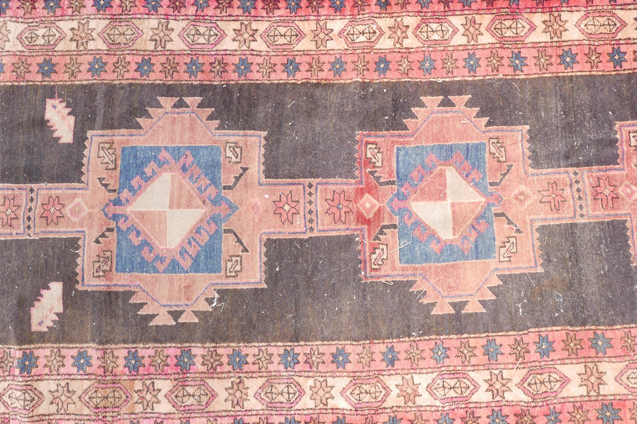 A Persian black ground hand woven wool runner with a repeating rust coloured medallion design within