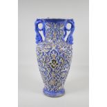 A Persian blue ground pottery two handled vase, with iznik style raised polychrome scrolling