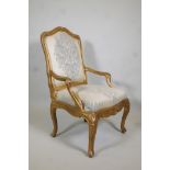 An early C19th giltwood open-arm chair, with shaped back and arms, carved details and a serpentine