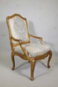 An early C19th giltwood open-arm chair, with shaped back and arms, carved details and a serpentine