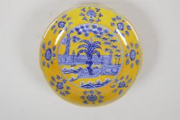 A Ming style yellow ground porcelain dish with blue and white decoration of an ornamental garden,
