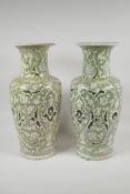 A pair of Persian pottery vases, with green iznik scrolling decoration. Signed to the rim. AF,