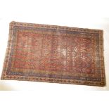 an antique hand woven Persian carpet with geometric designs on a red field with blue borders, 46"