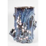 An Oriental stoneware vase, formed as a tree trunk with embossed prunus blossom, on a flambe