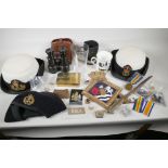 A collection of military and naval ephemera to include WWI binoculars, Wren's hats, bayonet, replica