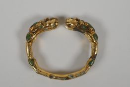 A gilt metal bangle with twin dragon head decoration, set with turquoise stones. 3" x 2½"