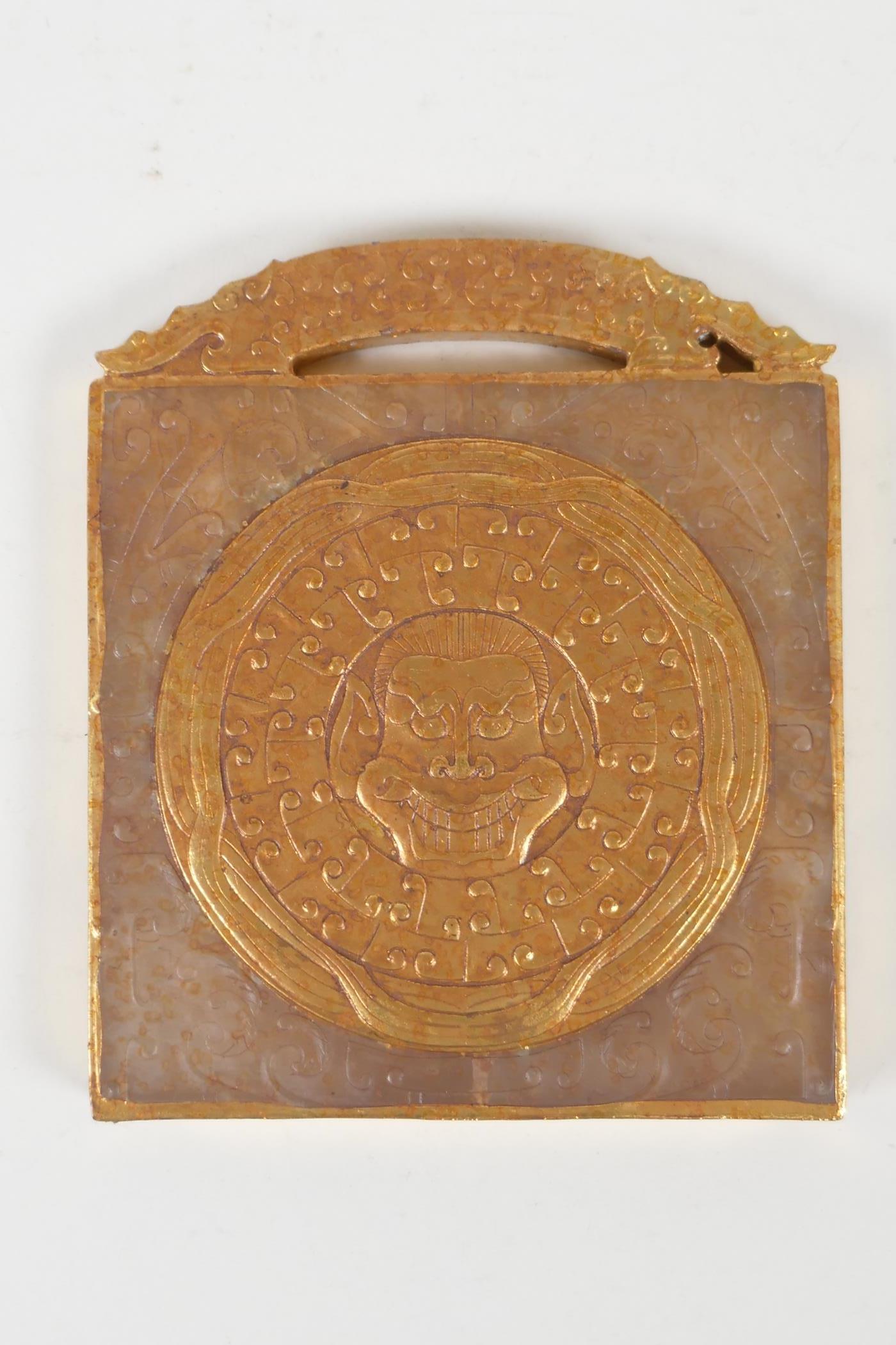 A Chinese carved and gilt hardstone tablet/scroll weight with dragon mask decoration, 3½" x 4½"