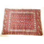 A vintage Bokhara hand woven wool carpet with central geometric pattern on a red field with white