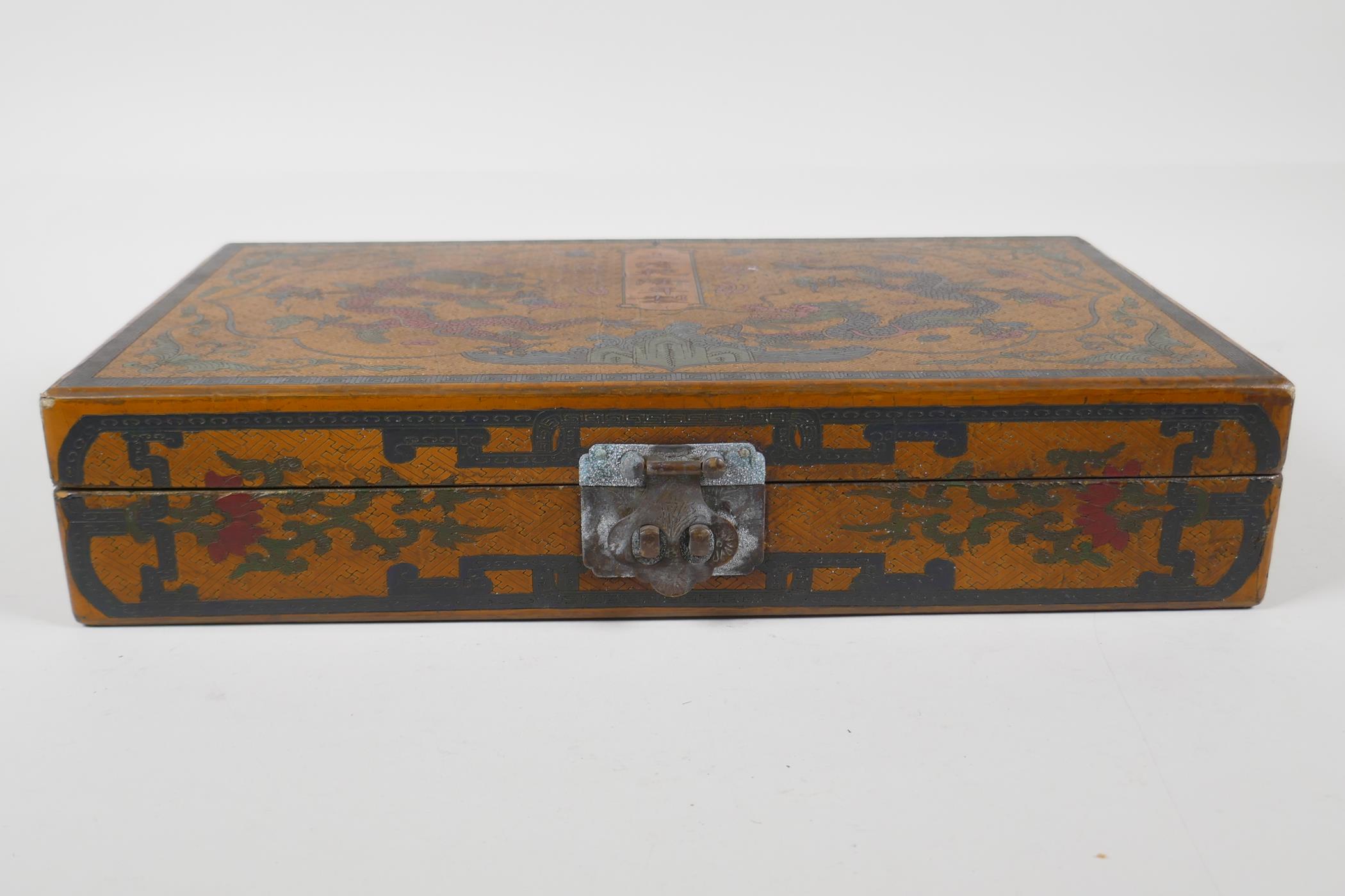 A Chinese ochre ground lacquer box with chased and painted decoration of dragons and character