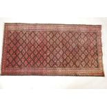 A hand woven rug with geometric floral design, on a faded red field. 41" x 78"