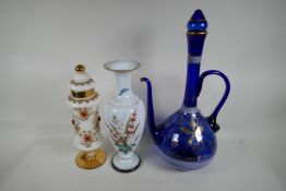 A gilt decorated blue glass wine ewer and stopper, 19" high, a milk glass vase painted with flowers,