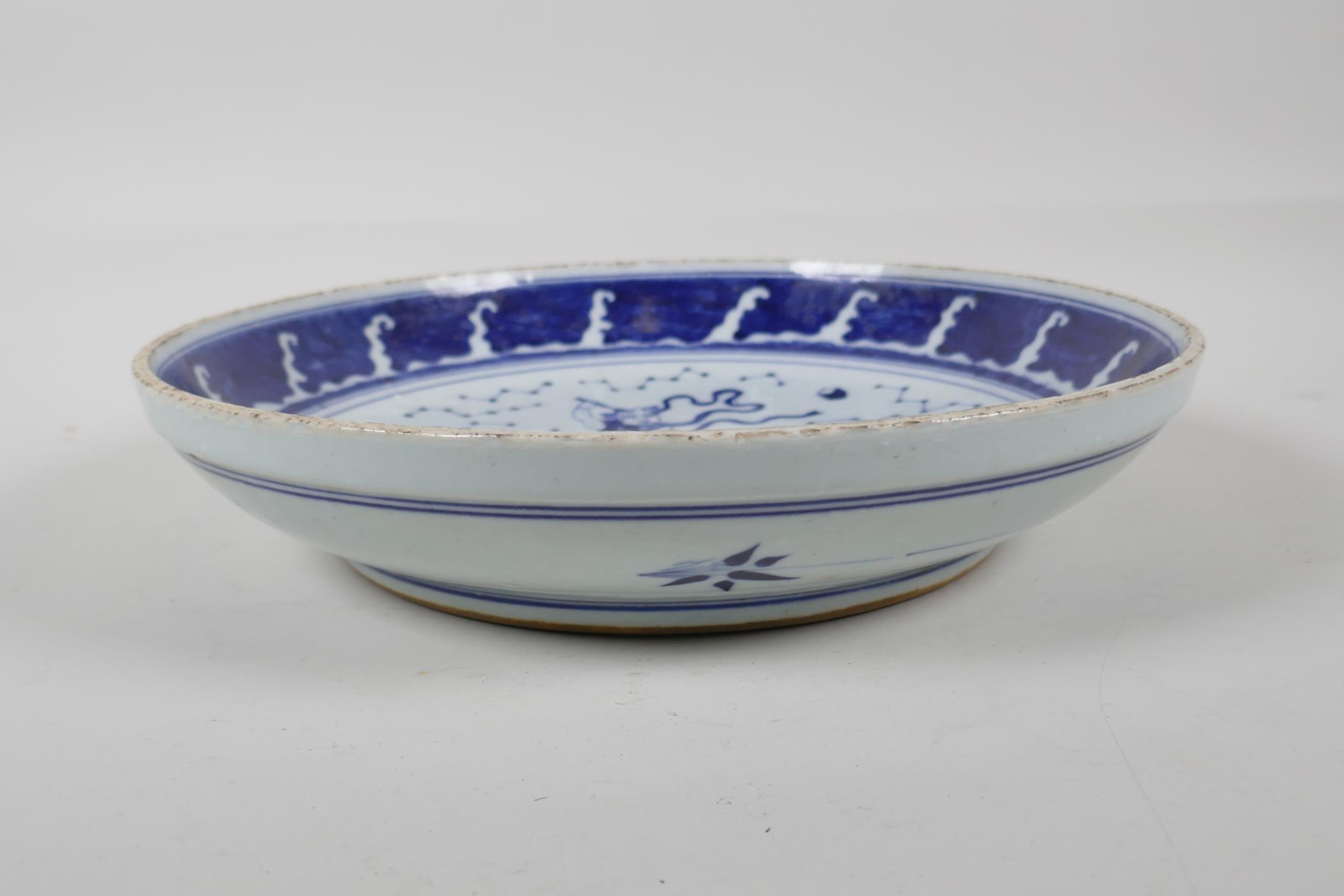 A Chinese Republic period blue and white porcelain dish decorated with Qingao riding a carp, 11½" - Image 2 of 3