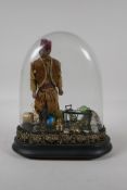 An antique glass dome & stand, containing a diorama of an Eastern gent & his wares. 10" high