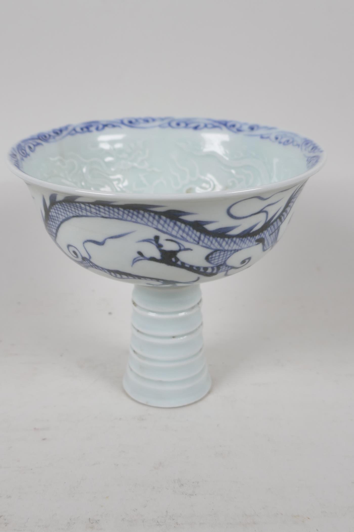 A Chinese blue & white porcelain stem cup, painted and embossed with dragons and clouds. 5" diameter